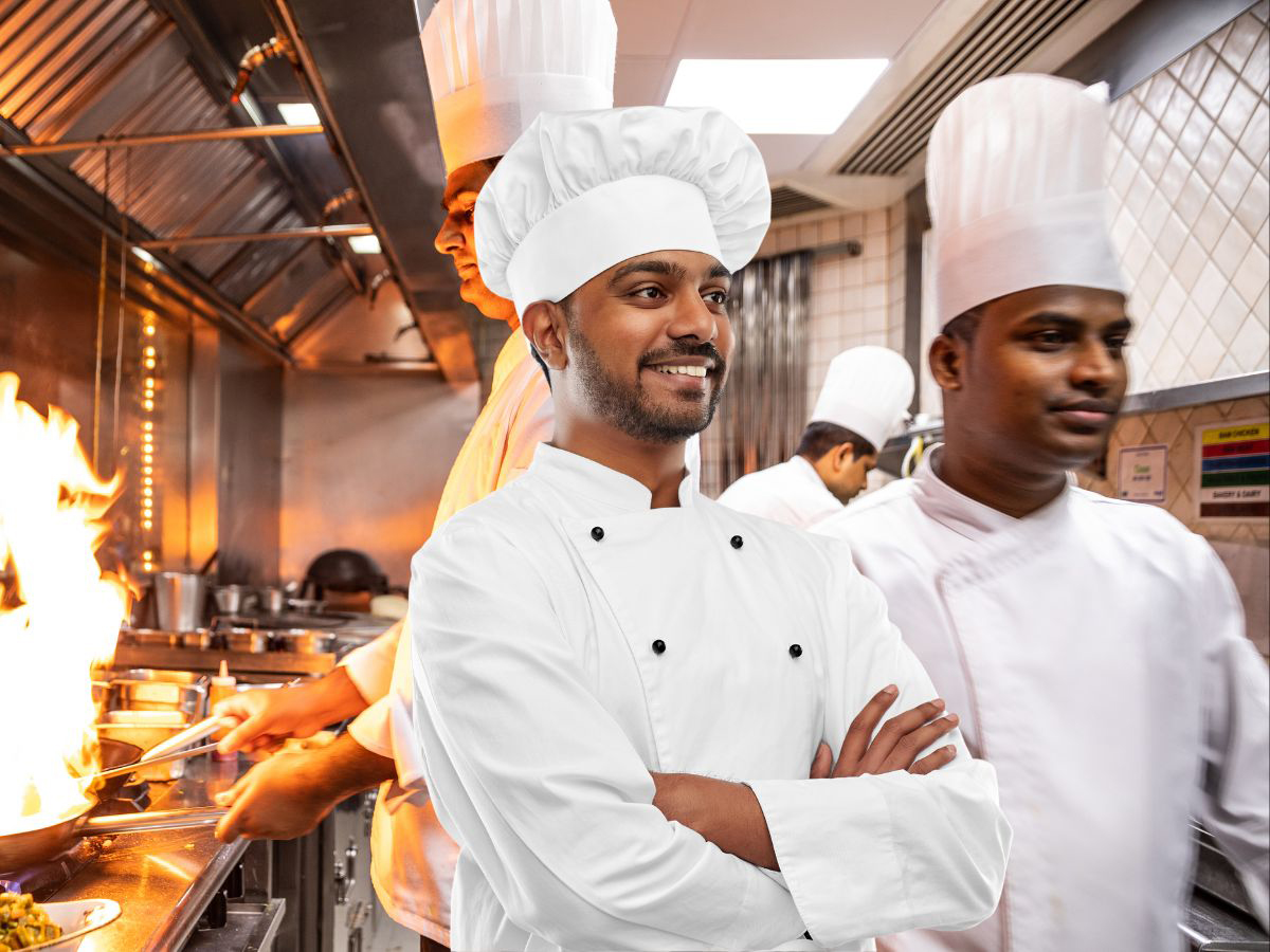 An Indian chef expertly crafting a dish at Tasty Treat Restaurant, showcasing the mastery of spices and culinary skills in every flavorful creation